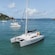 Catamaran anchored in a bay, surrounded by sailboats and lush green hillsides